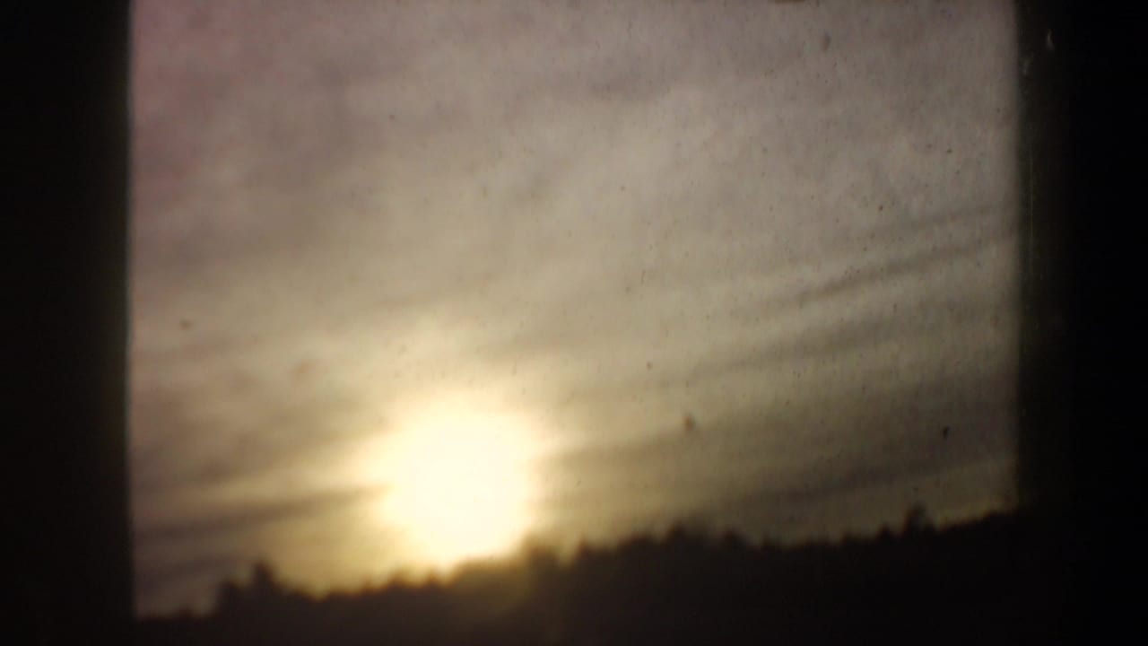 Final 8mm frame from the clip showing a low sun above a dark winter treeline, likely part of the same 1962 New Hampshire reel.