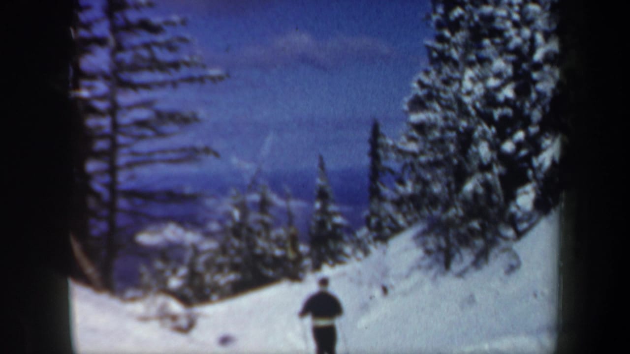 The skier appears farther down the 1962 New Hampshire slope, framed by snowbanks, evergreen trees, and distant blue mountains.