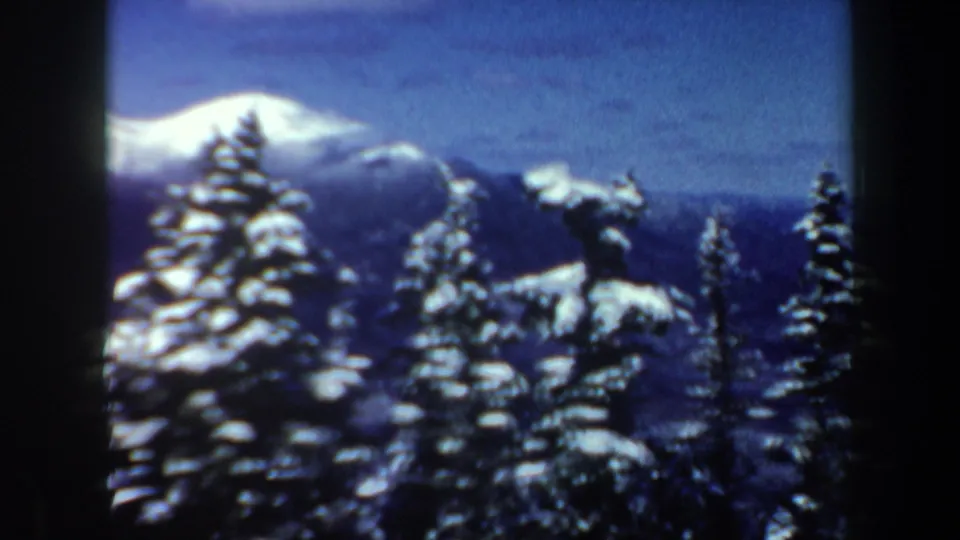 1962 New Hampshire home-movie frame showing a wide winter mountain vista with snow-covered trees and distant peaks.