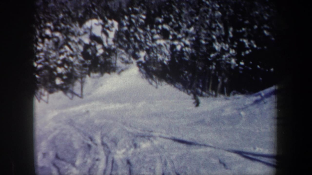 1962 New Hampshire 8mm frame of a snow-covered slope and forest edge, with ski tracks visible in the foreground.