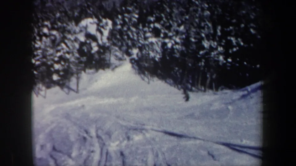 1962 New Hampshire 8mm frame of a snow-covered slope and forest edge, with ski tracks visible in the foreground.