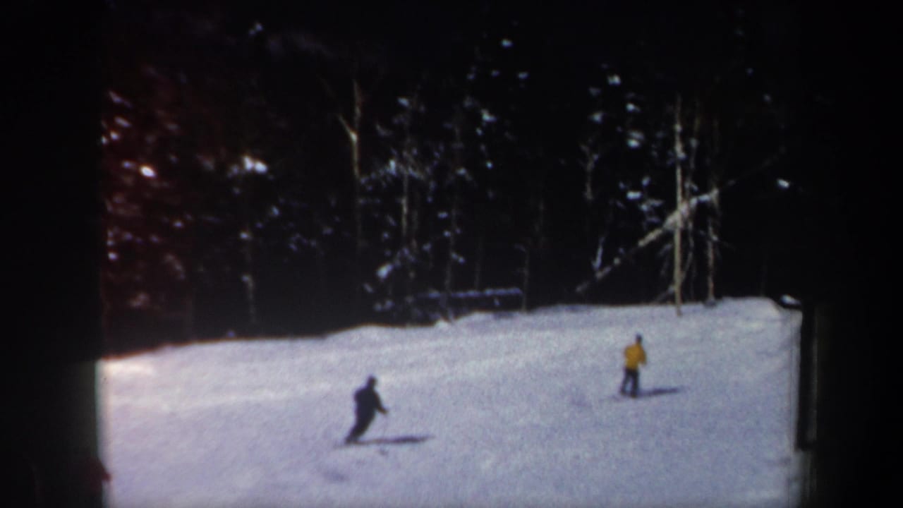 Two visible skiers cross the snow while another may be out of frame in this 1962 New Hampshire ski scene.