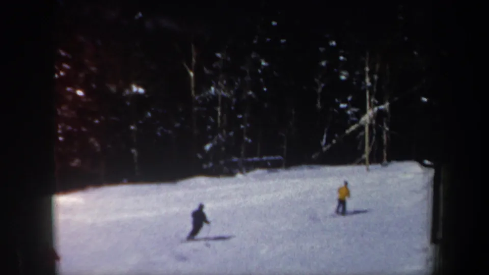 Two visible skiers cross the snow while another may be out of frame in this 1962 New Hampshire ski scene.
