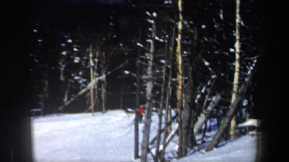1962 New Hampshire ski footage frame with a small skier near a wooded edge on a white winter slope.