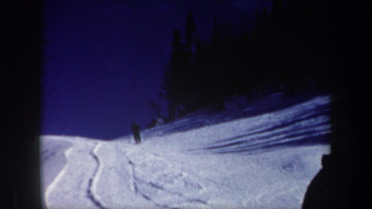 Wide 1962 New Hampshire ski scene with tracks in powder, long tree shadows, and a lone skier on the slope.
