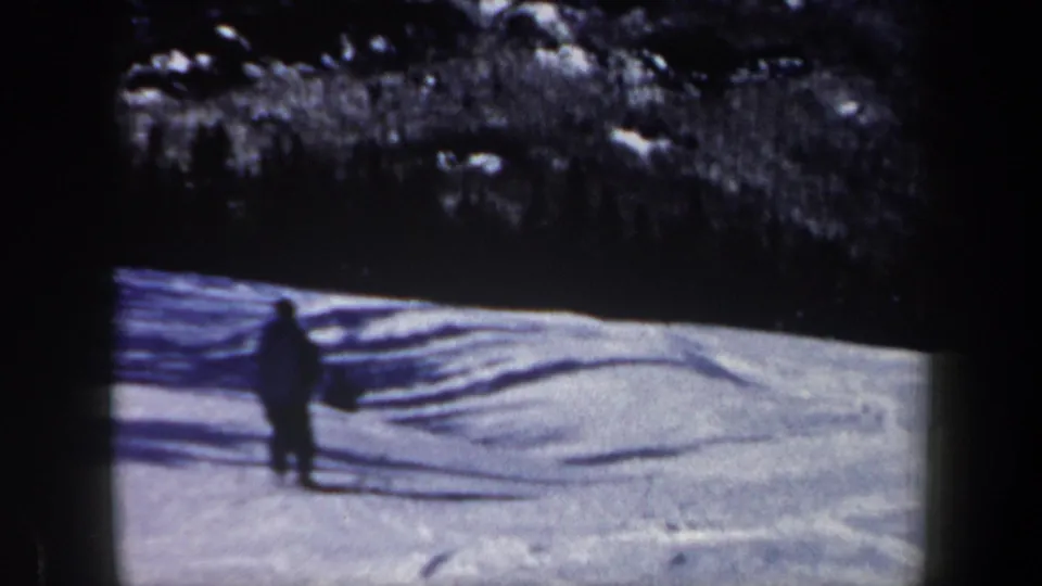 The skier appears farther down the snowy New Hampshire slope, silhouetted against pale snow and dark trees.