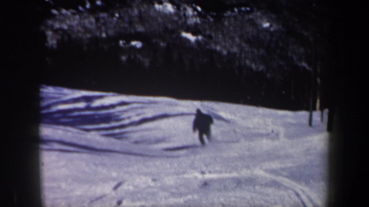 A dark-clad skier continues downhill on a snowy New Hampshire slope in grainy 1962 8mm footage.