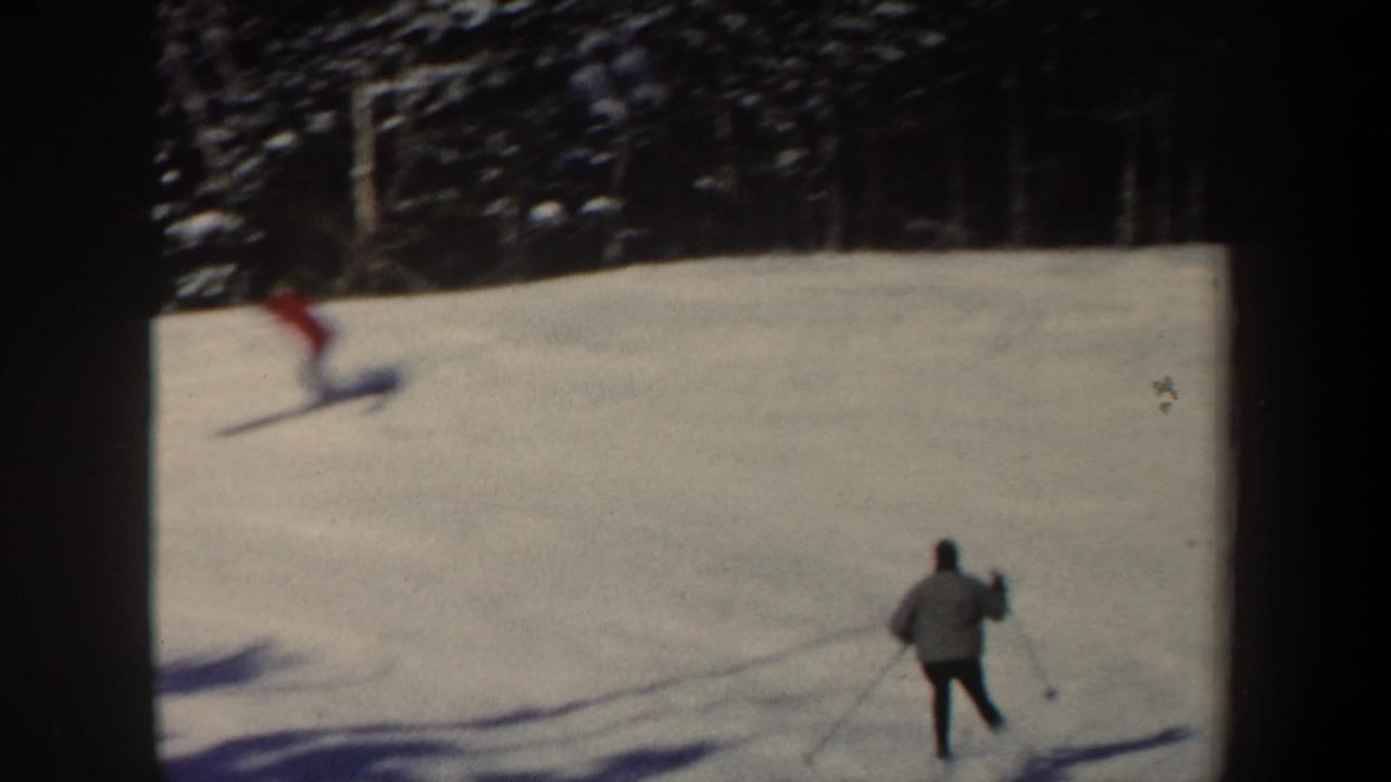 1962 New Hampshire skiing scene with one skier descending the slope and another distant figure standing with poles near the lower right.