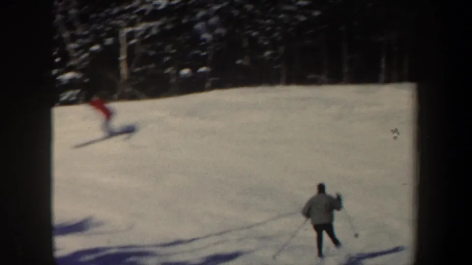 1962 New Hampshire skiing scene with one skier descending the slope and another distant figure standing with poles near the lower right.
