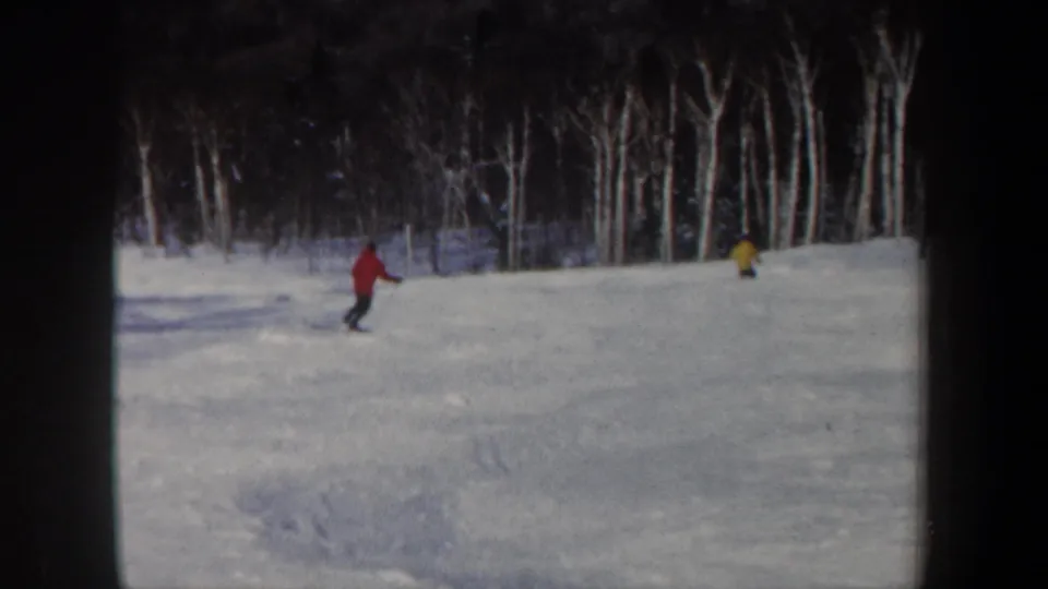 1962 New Hampshire 8mm frame with red- and yellow-jacketed skiers on a snowy slope near bare trees.