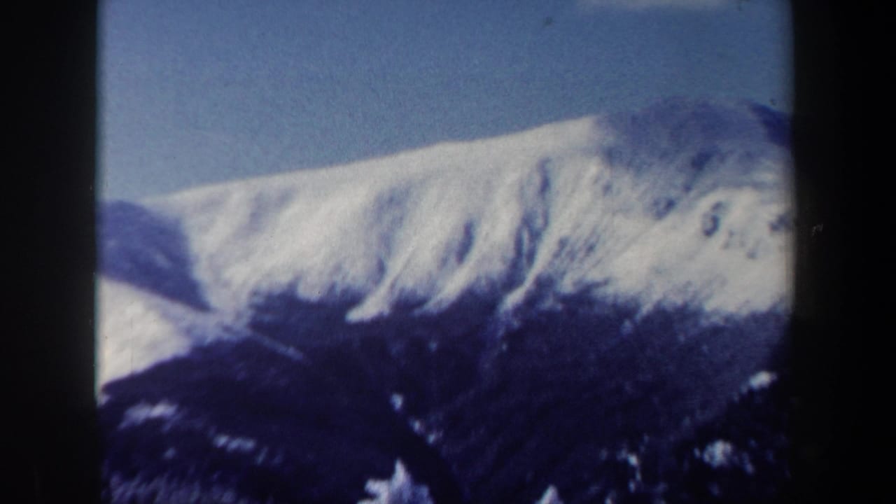 A snow-covered mountain ridge fills the frame under clear blue sky in the New Hampshire winter landscape shot.