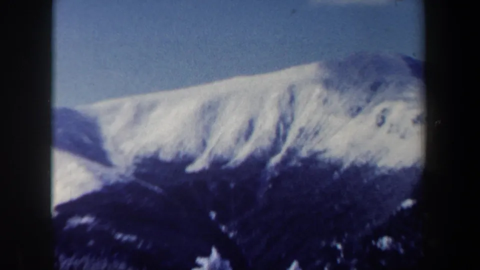 A snow-covered mountain ridge fills the frame under clear blue sky in the New Hampshire winter landscape shot.