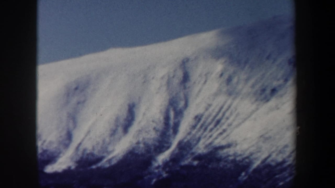 A zoomed view shows a snowy mountain face and ridgeline beneath clear sky in the New Hampshire winter scene.