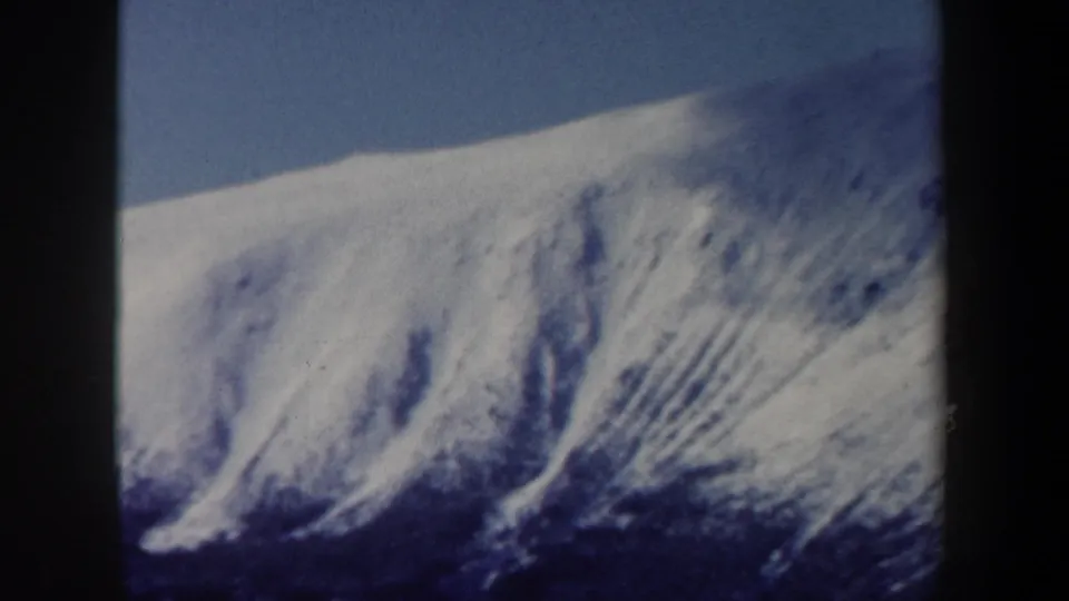 A zoomed view shows a snowy mountain face and ridgeline beneath clear sky in the New Hampshire winter scene.