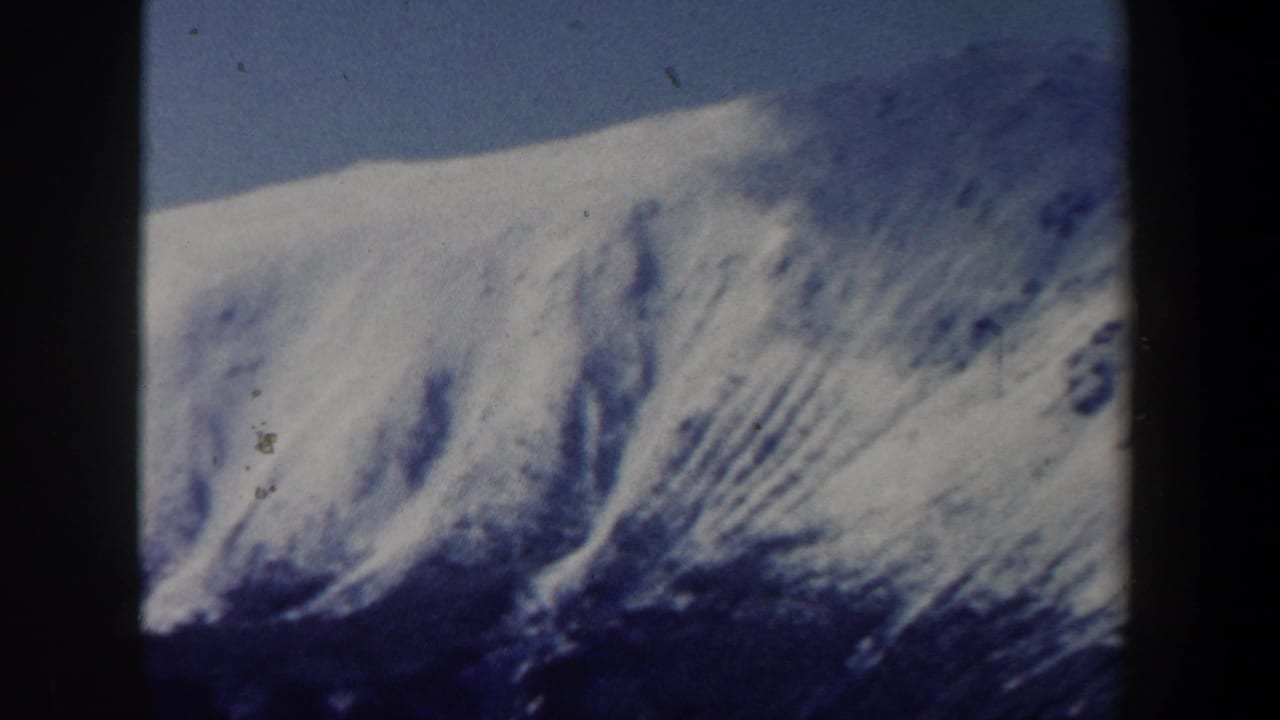 1962 New Hampshire 8mm frame showing a snow-covered mountain slope with shadowed ridges and a dark contact-sheet divider.