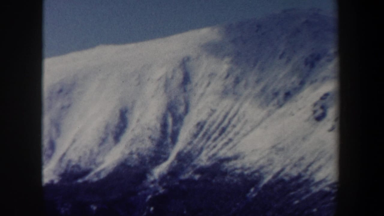 Snowy mountain ridge with streaked shadows and blue sky, bordered by contact-sheet dividers.