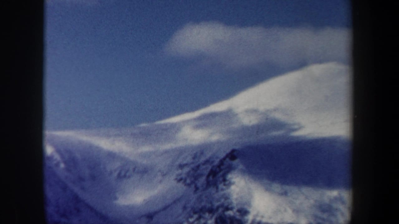 1962 New Hampshire 8mm frame showing a snowy mountain ridge beneath a blue sky, with visible contact-sheet borders.