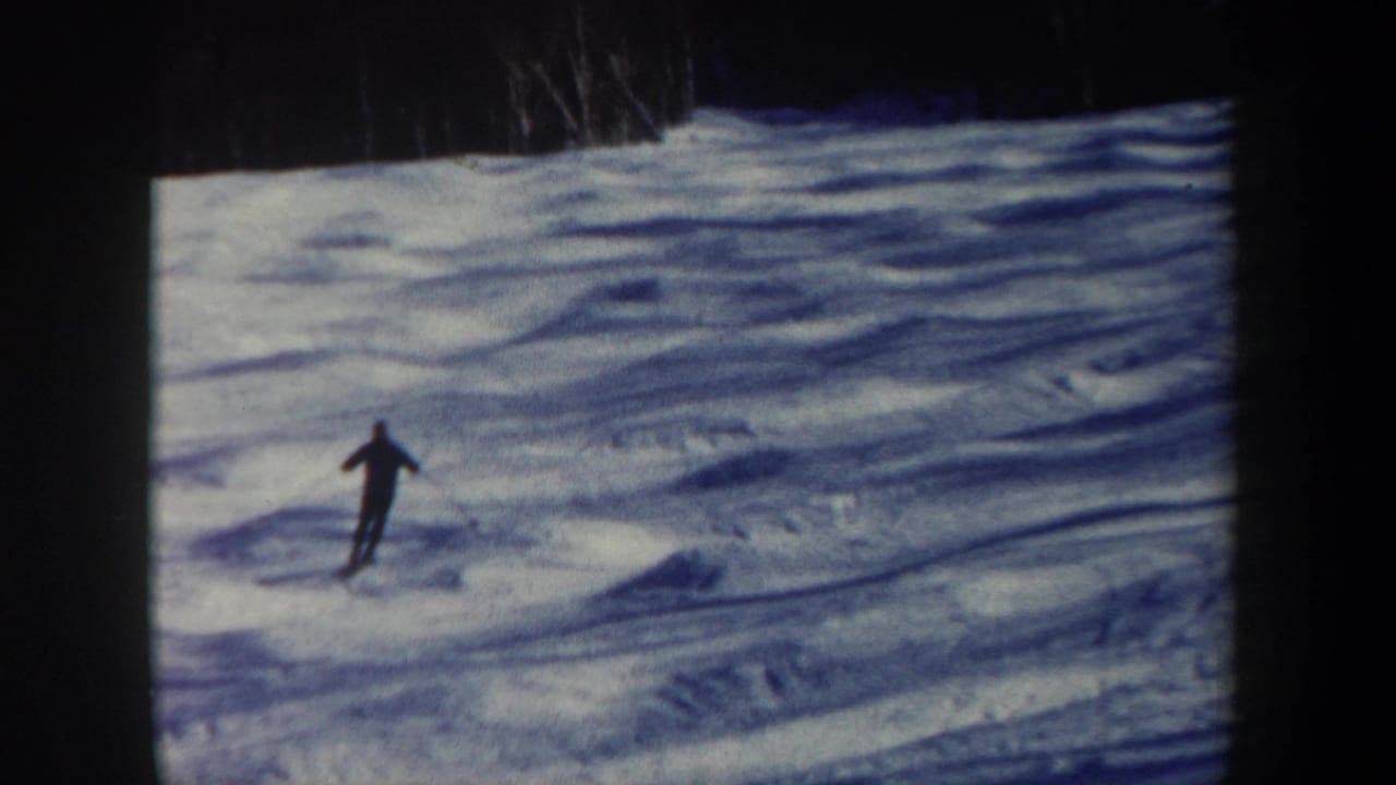 Skier centered on a snow-covered hill with arms out for balance.