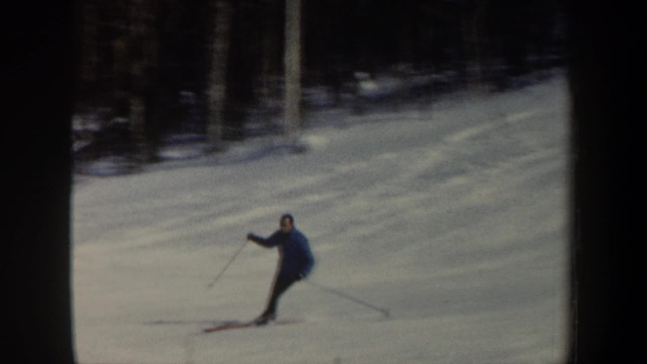 Skier in a blue jacket turns on a snowy slope.