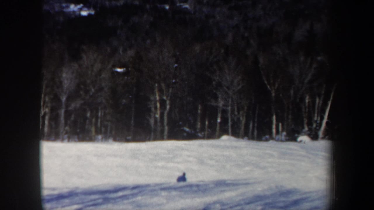 The skier is seen small against the snowfield, with bare trees and shadowed snow in the 1962 New Hampshire scene.