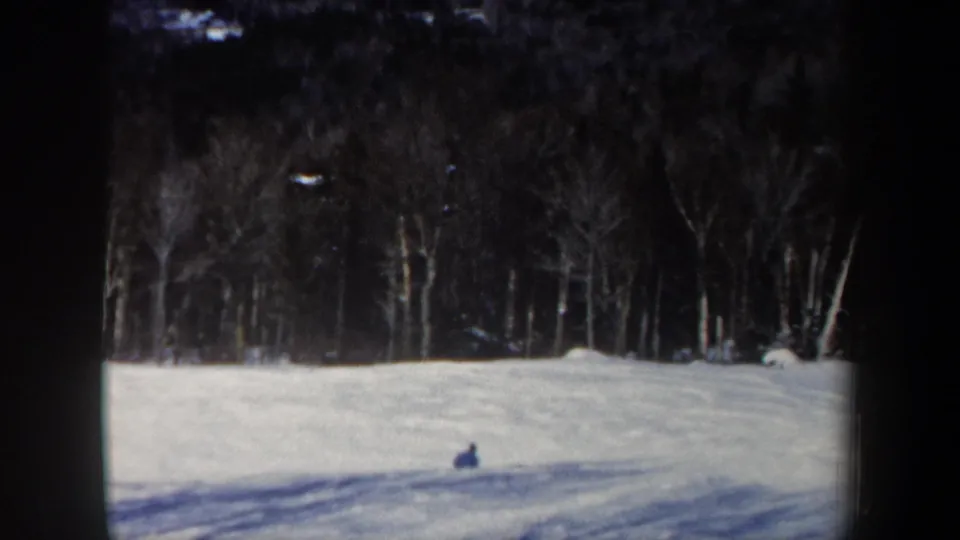 The skier is seen small against the snowfield, with bare trees and shadowed snow in the 1962 New Hampshire scene.