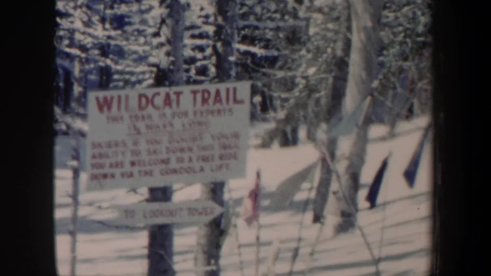Another close home-movie view of the Wildcat Trail sign in New Hampshire snow, with trees and trail information visible.