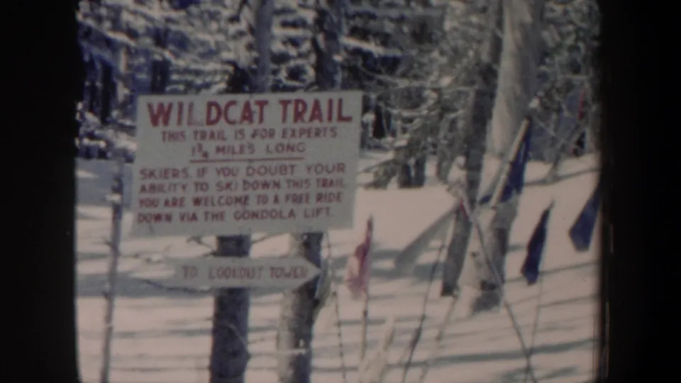 The Wildcat Trail sign remains centered, with snow, woods, and slope poles visible in 1962 New Hampshire footage.