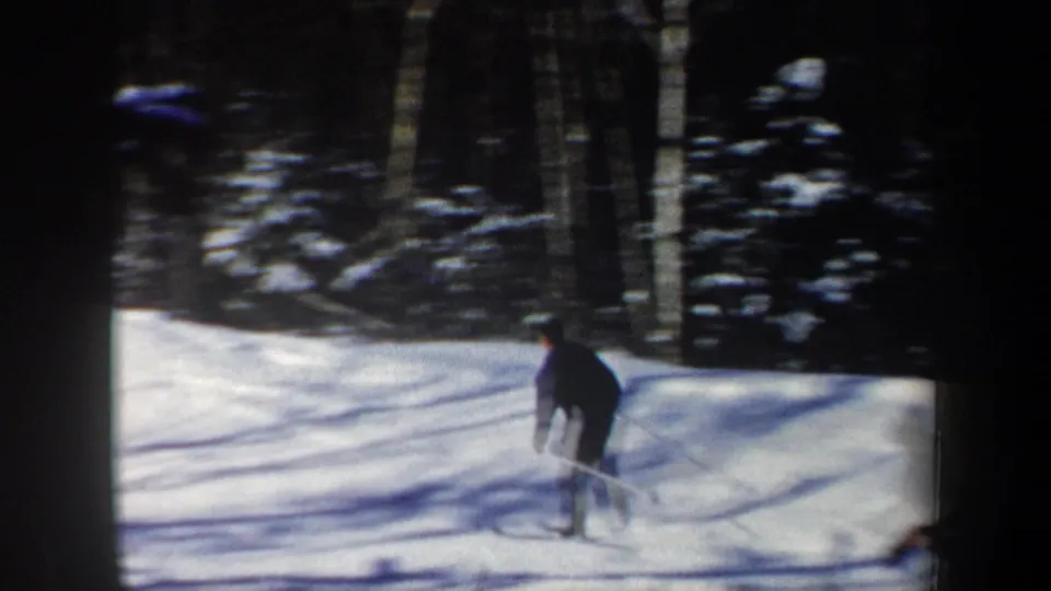 1962 New Hampshire 8mm frame showing a lone skier with poles on snow among bare trees.