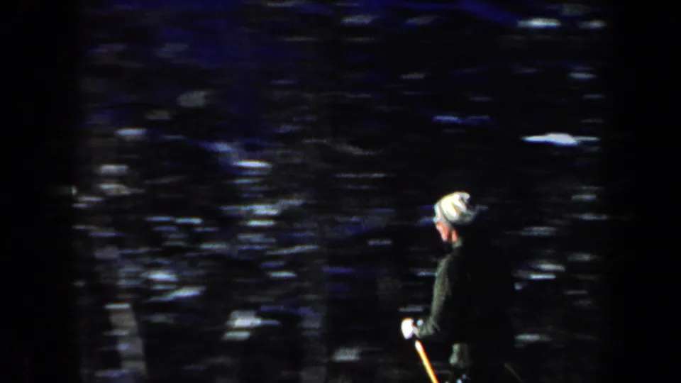1962 New Hampshire 8mm frame showing a skier in a light hat and dark jacket beside a snowy wooded area.