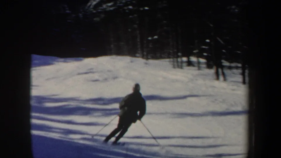 The skier appears farther down the New Hampshire slope, leaning into a turn with poles extended on the snow.