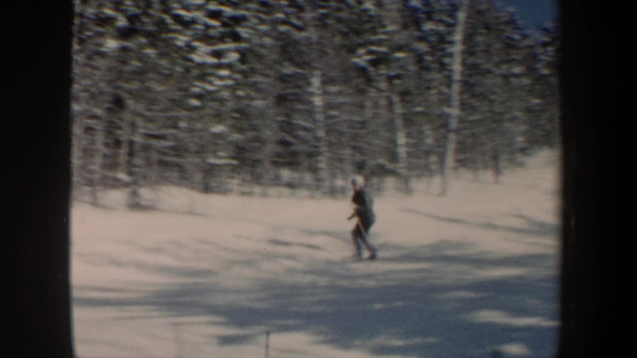 1962 New Hampshire 8mm frame showing a skier in dark winter clothing crossing a snowy wooded slope.