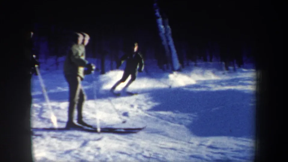 Two visible skiers in winter clothing navigate a snowy New Hampshire slope in this 1962 8mm home-movie frame.
