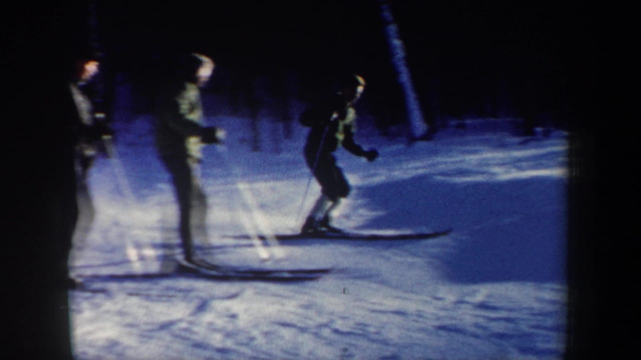 1962 New Hampshire ski footage frame with several people on skis near a wooded edge of a snowy hill.