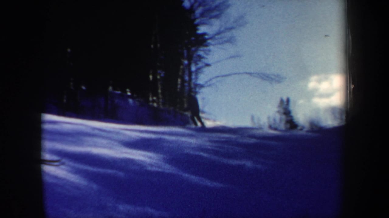 A skier moves down a New Hampshire snowy hillside in a blue-toned 1962 8mm home-movie frame.