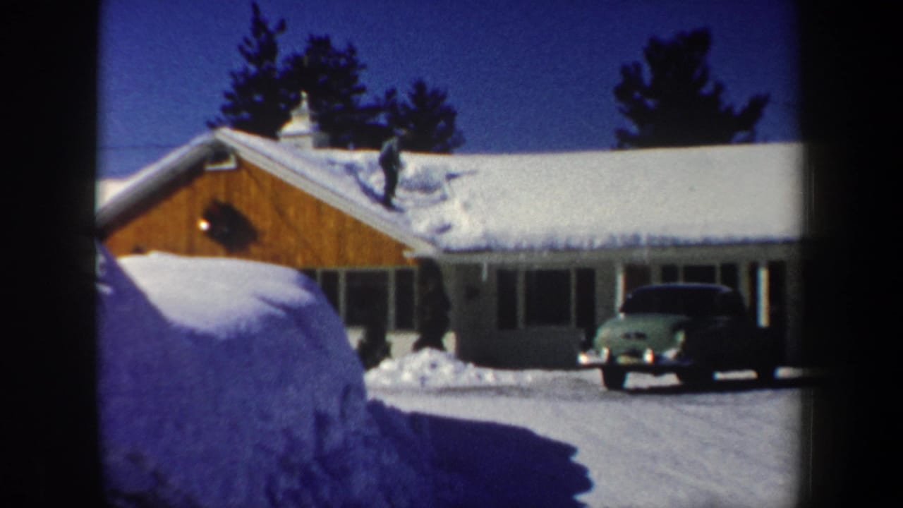 1962 New Hampshire frame of a snow-covered split-level house with a green older car in the driveway.