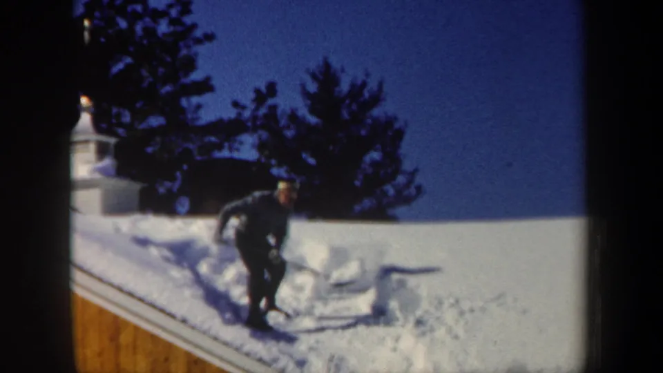 The final frame shows the man continuing to shovel roof snow, with evergreens and a cupola behind him.