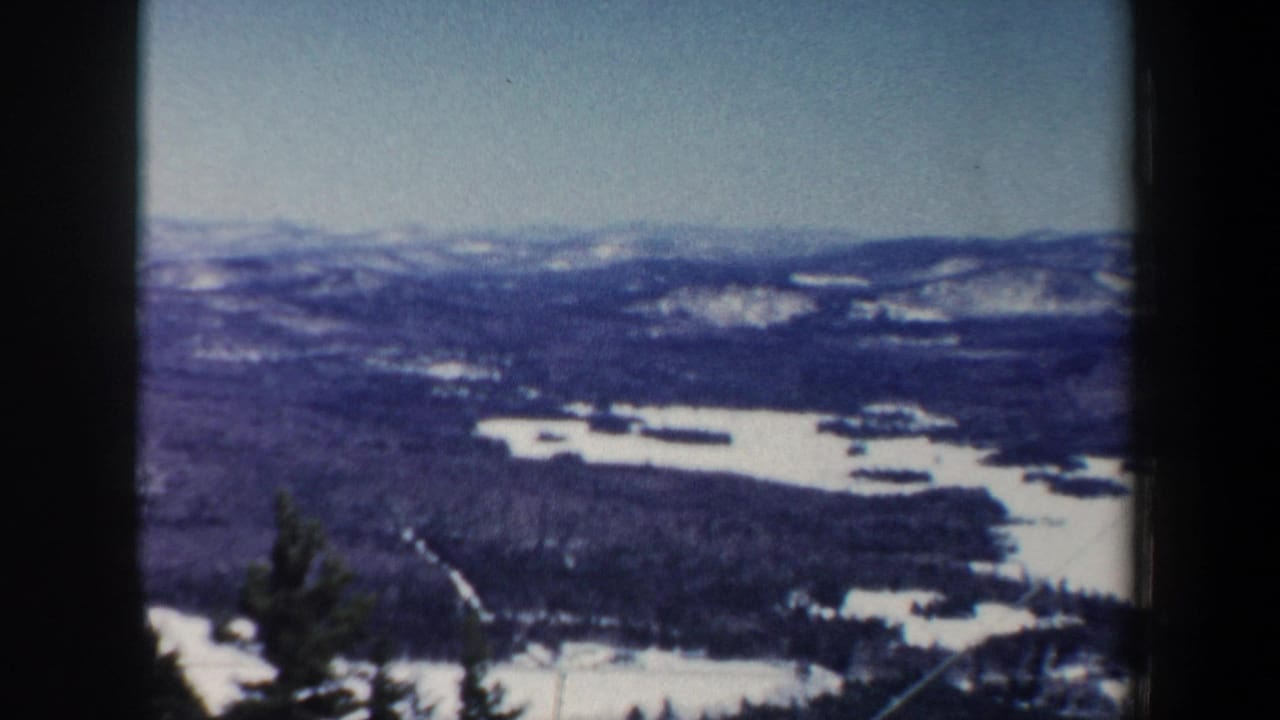 1962 New Hampshire 8mm frame showing snow-covered hills, forested valleys, and a winter sky from a high overlook.
