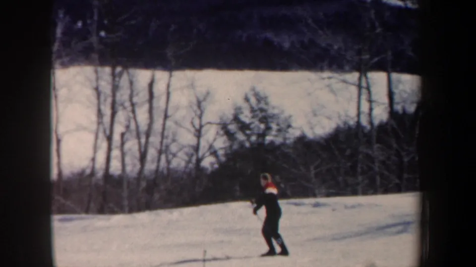 A lone skier in dark clothing appears near the lower part of a snowy New Hampshire slope in soft 8mm home-movie footage.