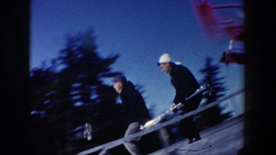 New Hampshire 1962 ski lift ramp scene with two people in winter clothing moving beside the lift equipment.