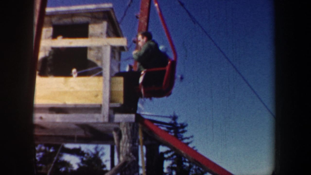 1962 New Hampshire 8mm frame with a skier on a red chairlift beside a small wooden lift station structure.