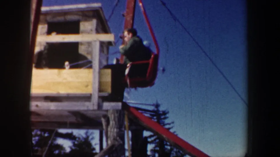 1962 New Hampshire 8mm frame with a skier on a red chairlift beside a small wooden lift station structure.