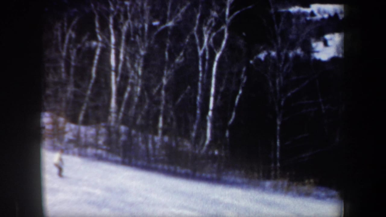 1962 New Hampshire home-movie frame showing a distant skier on a bright snowy slope near bare winter trees.