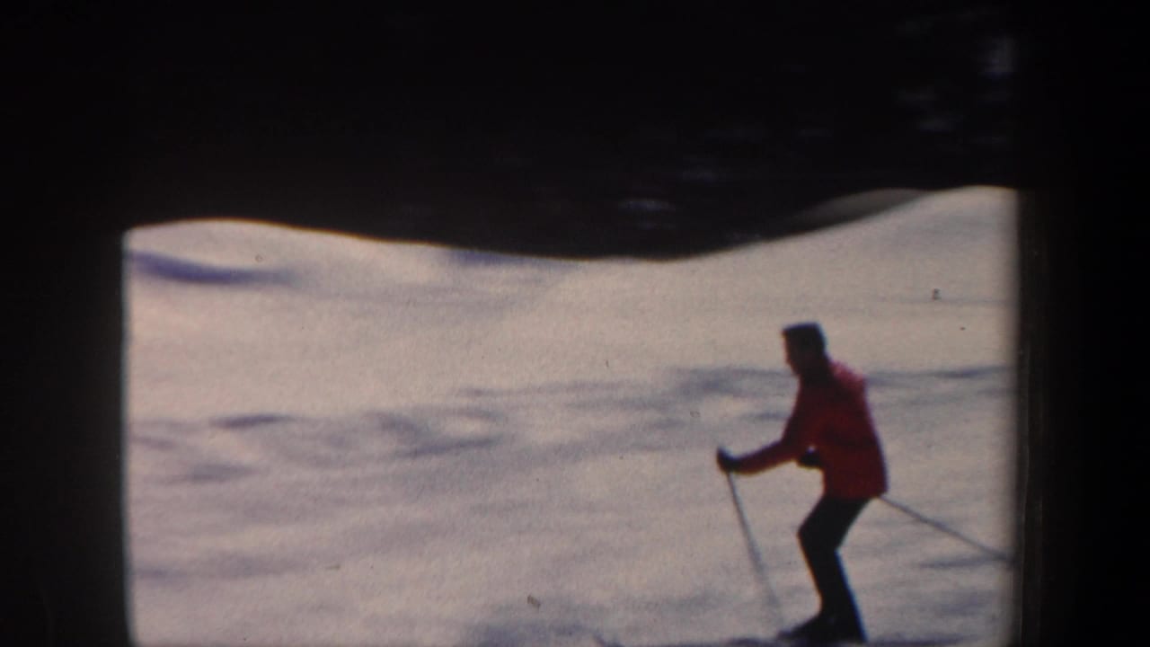 A skier in a red jacket moves across a snowy New Hampshire slope in this 1962 8mm home-movie frame.