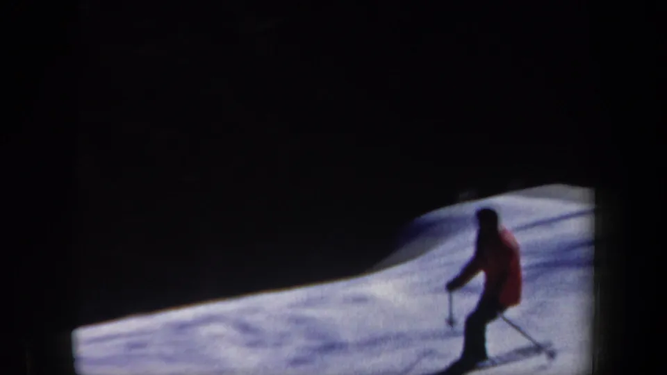 The skier appears farther back on the snowy slope, partly silhouetted by dark 8mm frame edges.