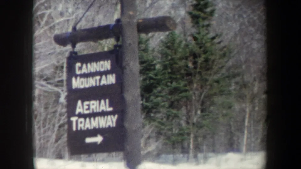 The final frame holds on the rustic Cannon Mountain Aerial Tramway sign, with evergreens, bare trees, and snow filling the background.