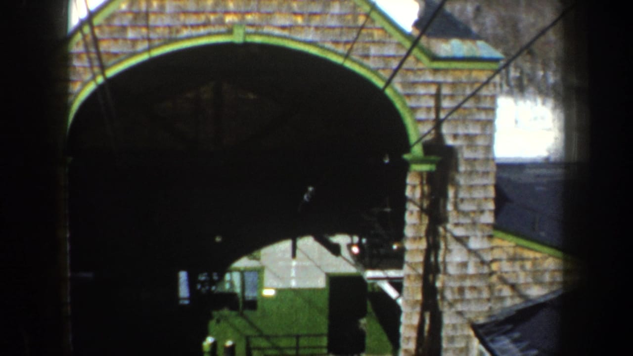 1962 New York home-movie frame showing a snow-dusted stone arch with green trim, viewed from a moving vantage point.