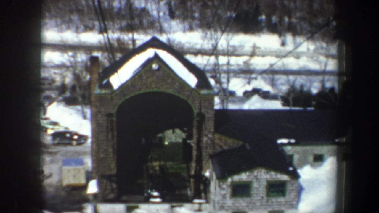 Stone archway and small snow-covered building seen from an elevated angle.