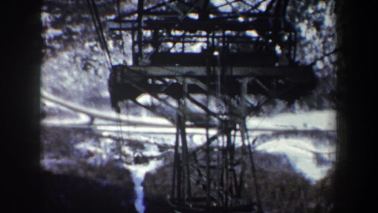 Red cable car partly visible beside steel towers over snowy wooded terrain.