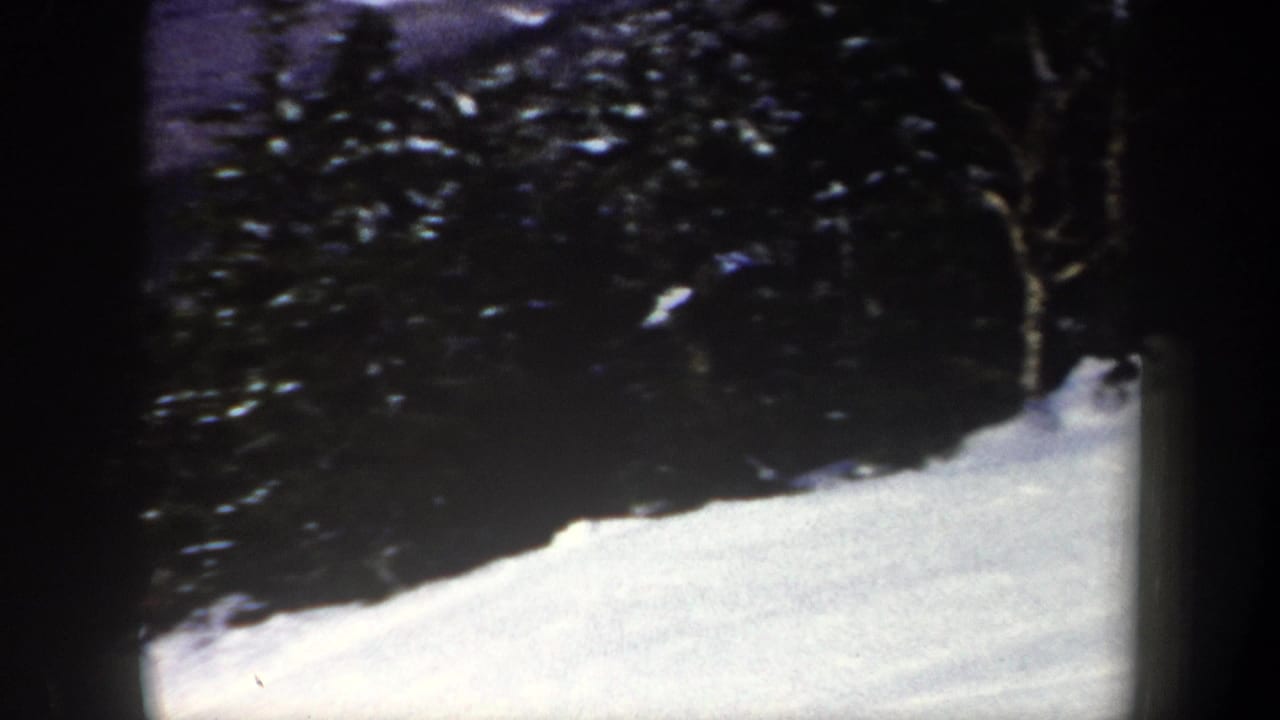 A snow-covered hillside in New York, 1962, framed by dark evergreen trees and rounded 8mm film borders.