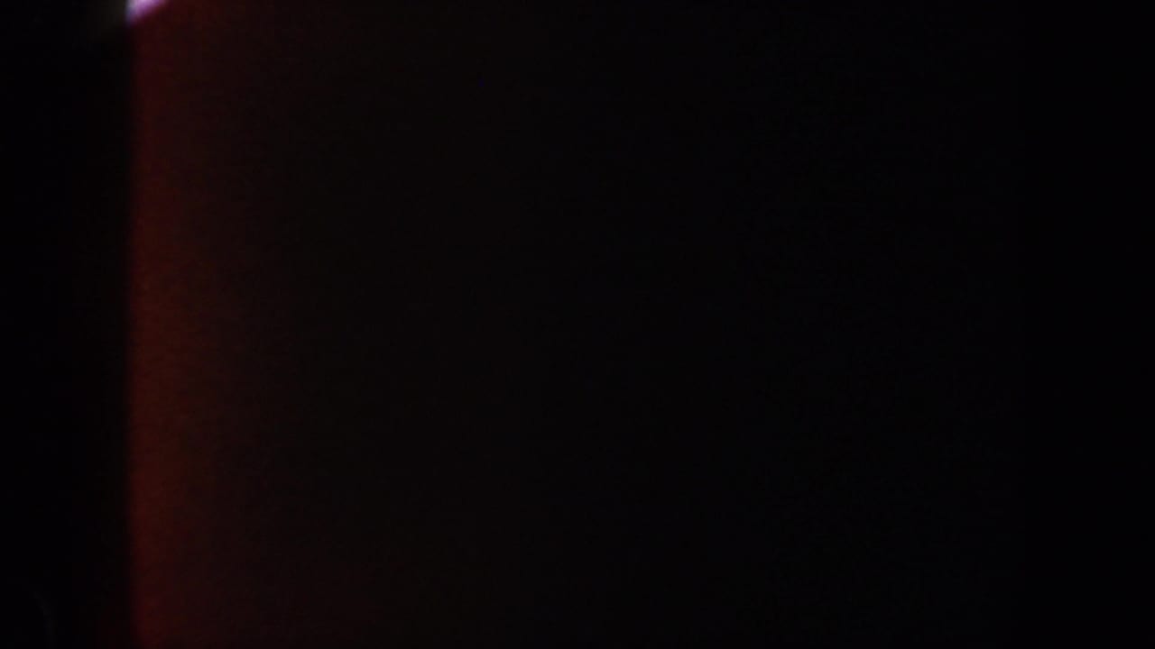 1962 New York 8mm frame showing dim orange light against a mostly black field with soft grain and uneven exposure.